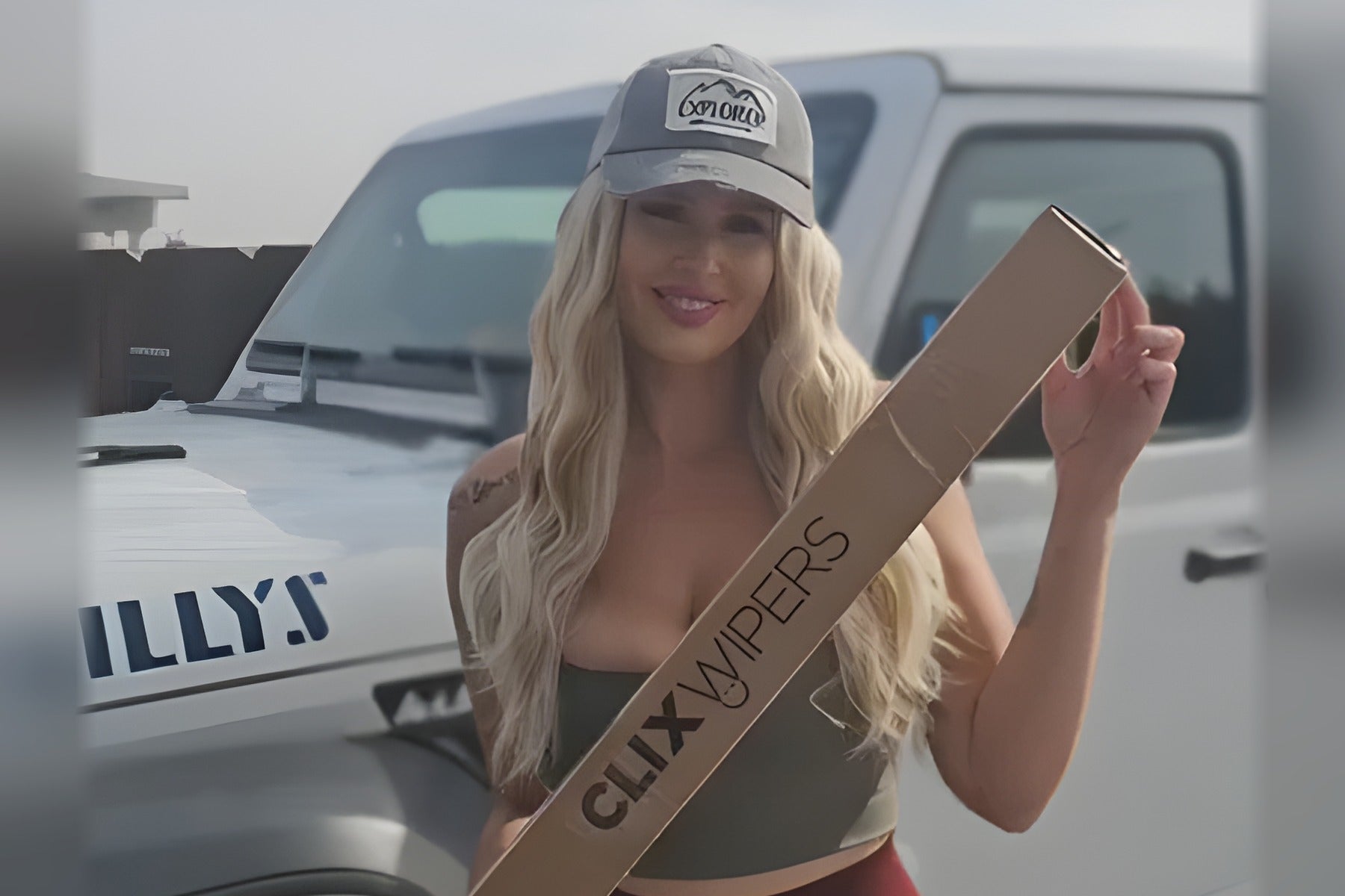 Woman holding a Clix Wipers box in front of a Jeep